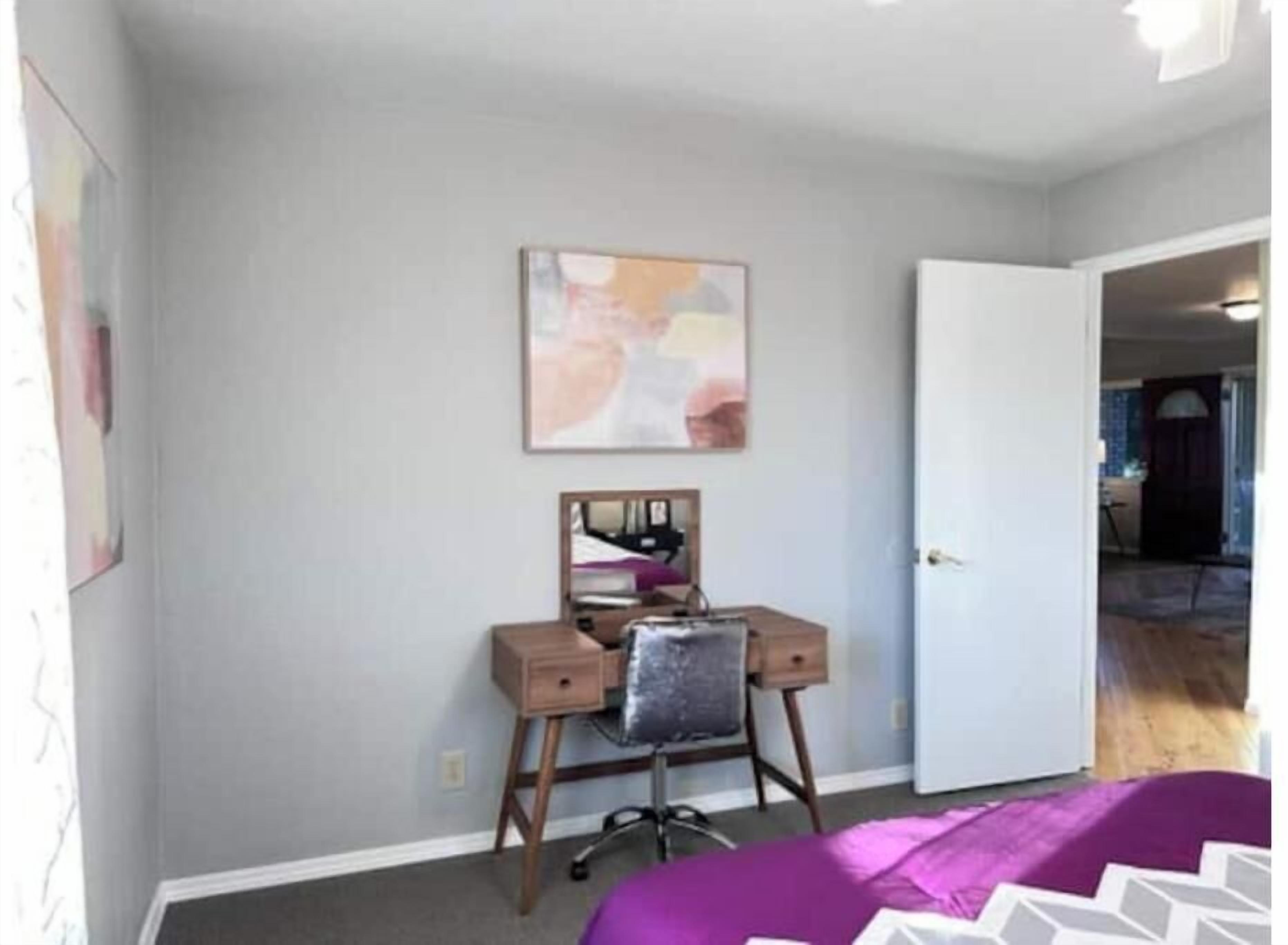 A bedroom with a desk, chair, and bed.