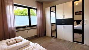 Ένα δωμάτιο ξενοδοχείου με δύο κρεβάτια, έναν μεγάλο καθρέφτη, μια ντουλάπα και θέα προς το εξωτερικό περιβάλλον.