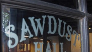A bar area with a sign reading "SAWDUST HALL" and a stool with a glass.