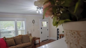 A living room with a sofa, a small table, a lamp, and a door with a welcome mat.