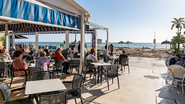 An outdoor café with tables and chairs, overlooking the beach. - MalagaSuite Tropical Pool (Torremolinos)