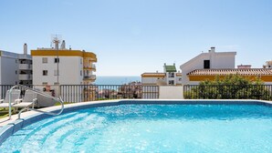 A swimming pool with a view of the sea, surrounded by buildings with balconies. - MalagaSuite Tropical Pool (Torremolinos)
