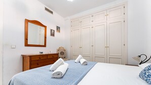 A bedroom with a bed, a dresser, a mirror, a wardrobe, and a bedside table. - MalagaSuite Tropical Pool (Torremolinos)
