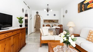 A living room with a TV, wooden cabinet, sofa, and coffee table. - MalagaSuite Tropical Pool (Torremolinos)