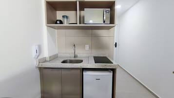 A compact kitchenette with a microwave, sink, and dishwasher.