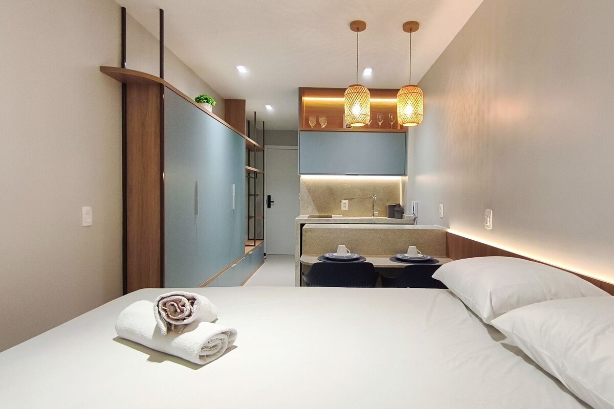 Una habitación de hotel moderna con una cama, un escritorio pequeño, un espejo y lámparas colgantes.