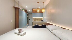 Una habitación de hotel moderna con una cama, un escritorio pequeño, un espejo y lámparas colgantes.