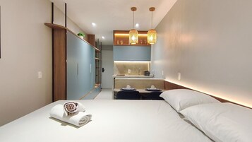 Una habitación de hotel moderna con una cama, un escritorio pequeño, un espejo y lámparas colgantes.