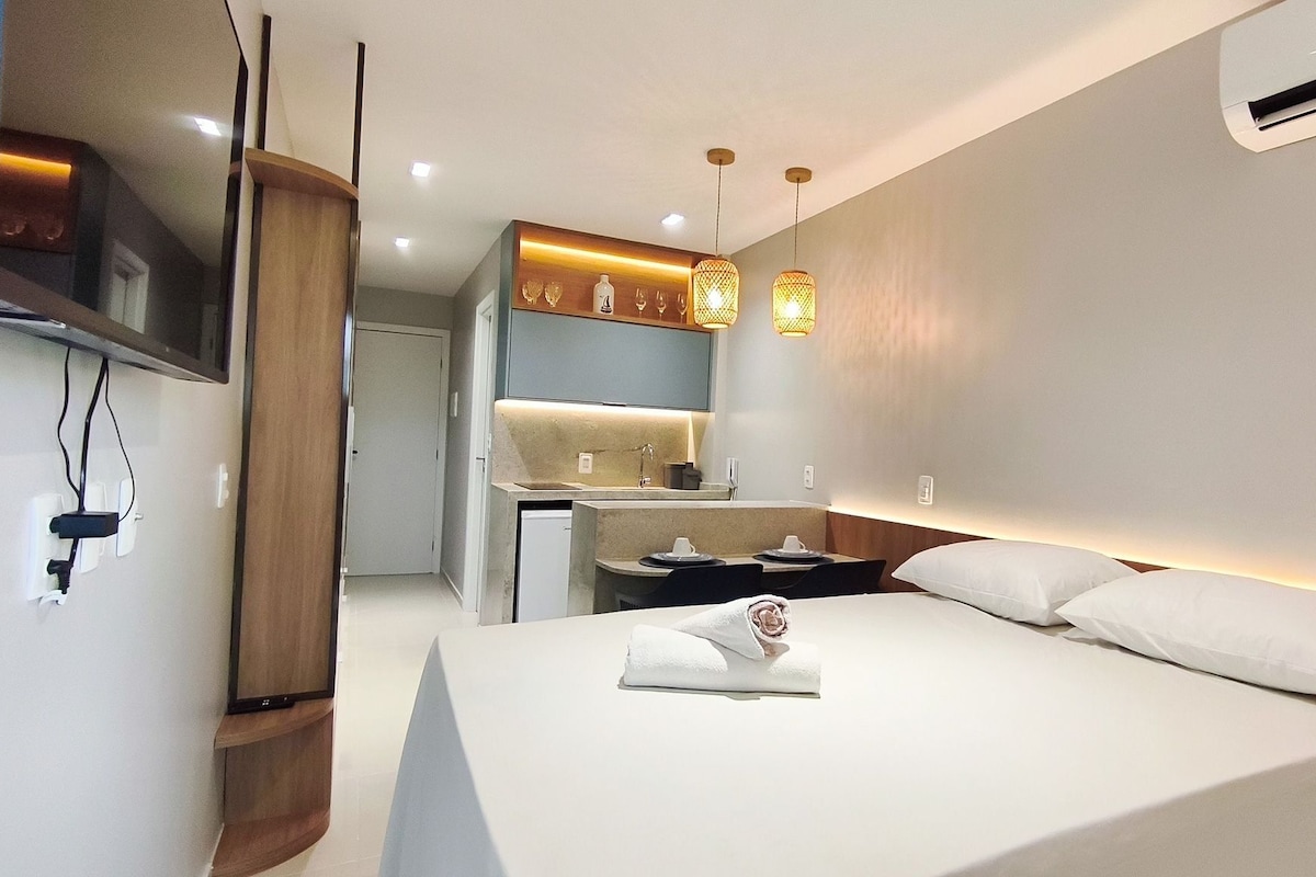A hotel room with a bed, a desk, a mirror, and a TV.