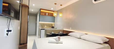 A hotel room with a bed, a desk, a mirror, and a TV.