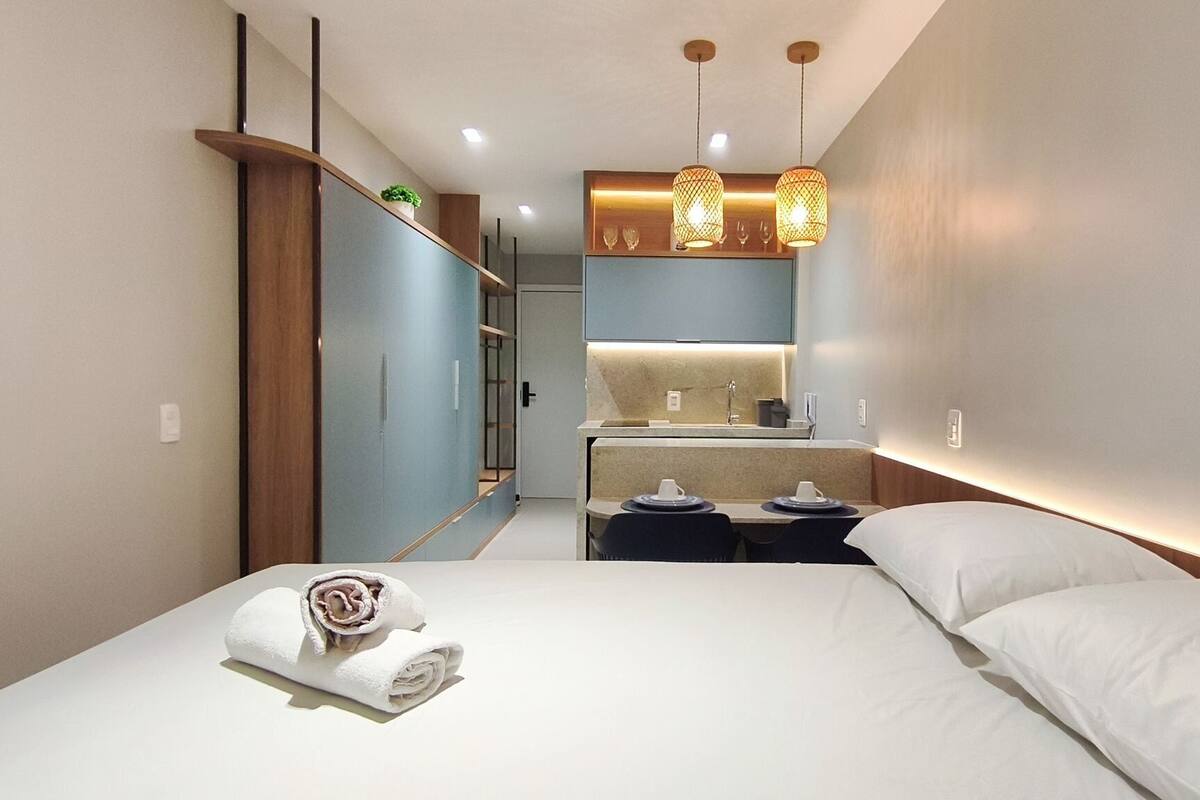 A modern hotel room with a bed, a small desk, a mirror, and pendant lights.