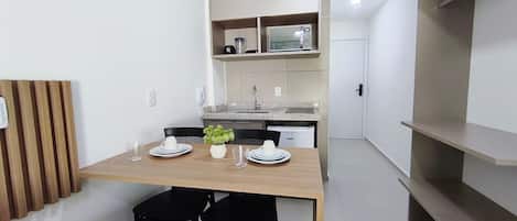 Une cuisine compacte équipée d’un four à micro-ondes, d’un évier et de placards. On y trouve une table à manger avec des chaises et une petite plante en pot.