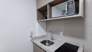 Una cocina con encimera de granito, pileta de acero inoxidable y un microondas arriba.