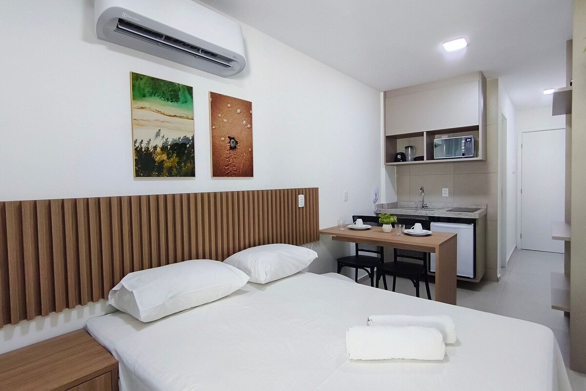 A hotel room with a bed, a desk, a microwave, and a small kitchenette.