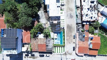 An aerial view of a residential area with solar panels, a swimming pool, and a street.
