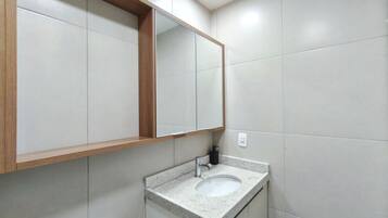 A bathroom with a sink, mirror, and tiled walls.