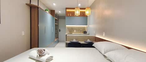 Una habitación de hotel moderna con una cama, un escritorio pequeño, un espejo y lámparas colgantes.
