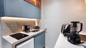 Cocina compacta con cafetera, tostadora y licuadora sobre la encimera.