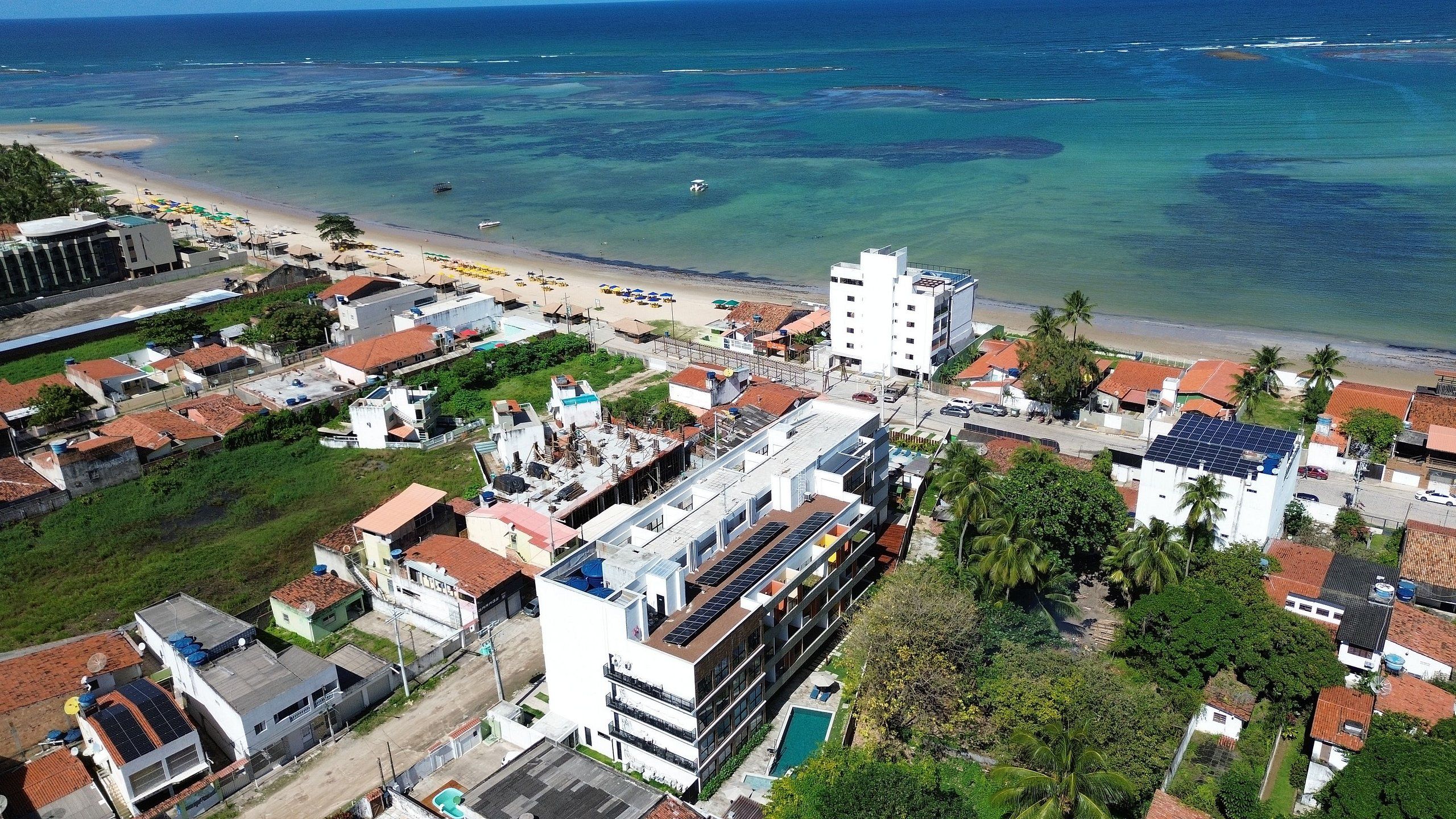 An aerial view of a coastal town with buildings, a beach, and a clear view of the ocean.