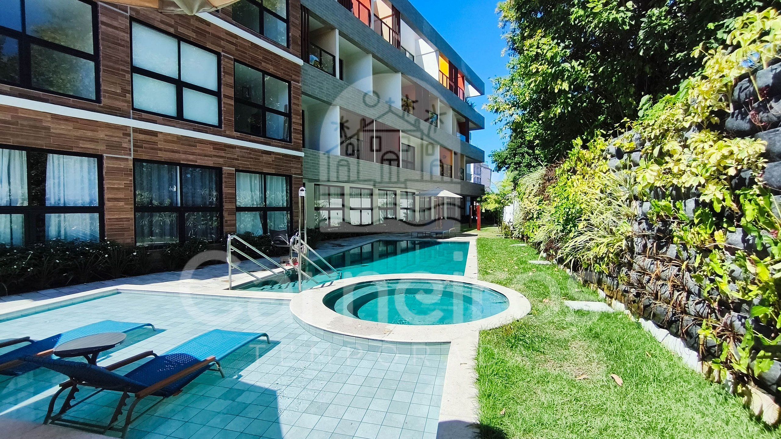 Un edifici modern amb piscina, zona de seients a l'exterior i jardí ben cuidat.
