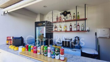 Una zona de bar con un refrigerador, estantes con botellas de licor y una variedad de bebidas en lata.