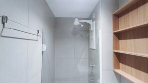 A modern bathroom with a glass shower enclosure, a towel rack, and a wooden shelf. - Maré Alta Beach Hall-Praia de Tamandaré (Tamandaré)