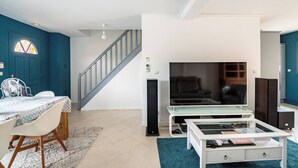 Ein modernes Wohnzimmer mit Treppe, Essbereich und einer TV-Anlage.