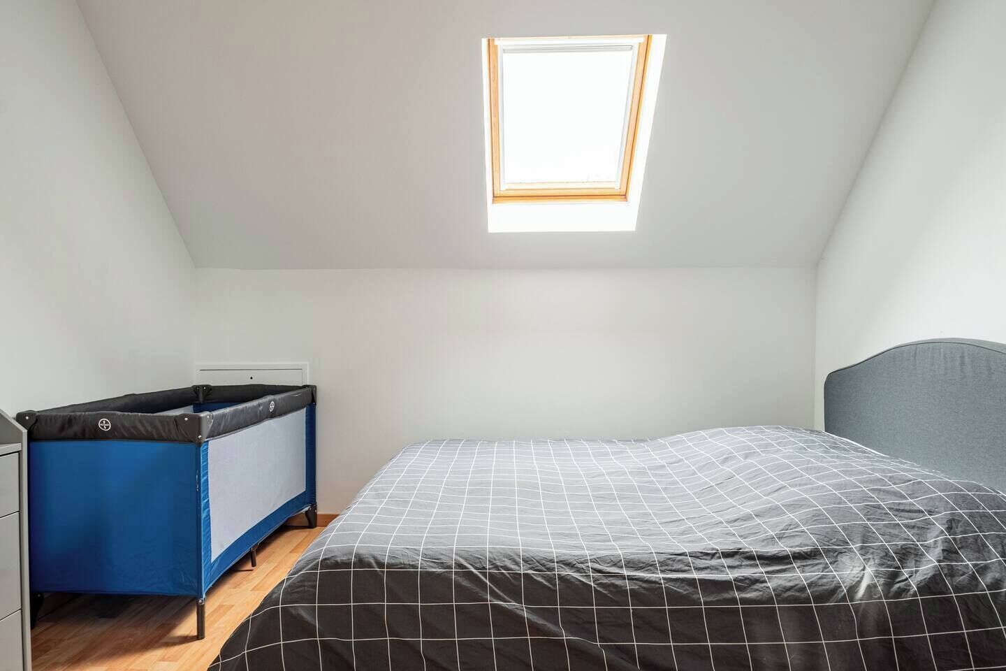 A small, single-bed room with a sloped ceiling and a skylight.