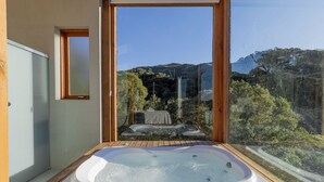 A modern bathroom with a wooden bathtub, a glass door, and a view of a waterfall and mountains. - Chalet in Mountains With Magnificent Views Vst017 (Anitapolis)