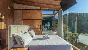 A bedroom with a large bed, a wooden headboard, a TV, and a view of a hot tub and landscape. - Chalet in Mountains With Magnificent Views Vst017 (Anitapolis)