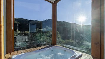 A hot tub on a wooden deck with a view of a mountainous landscape.