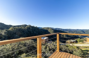 A wooden deck overlooking a mountainous landscape with a clear sky.