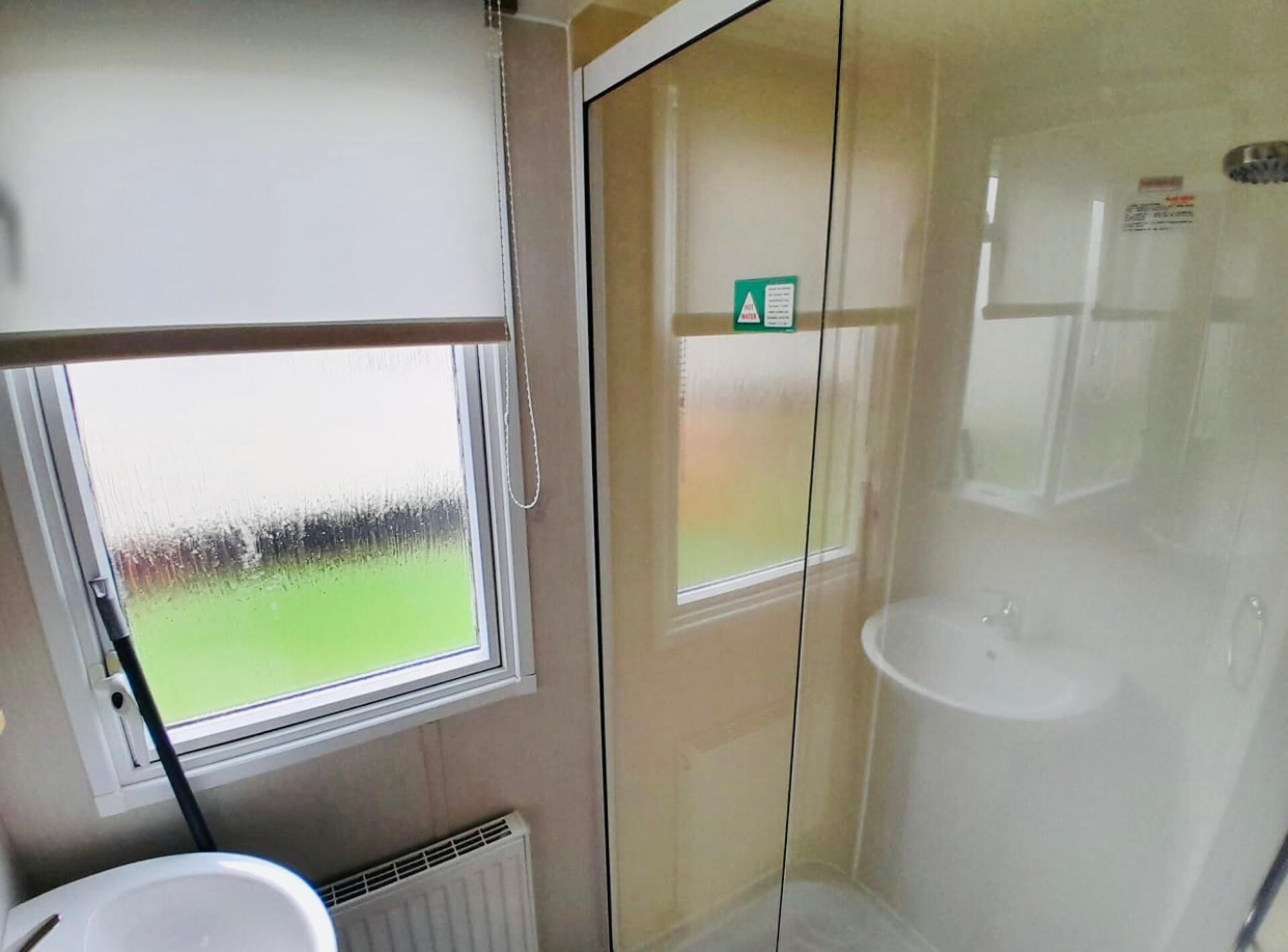 A bathroom with a window, a shower, and a toilet.
