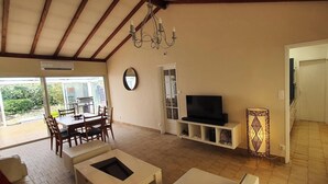 A spacious living room with a dining area, a TV, and a chandelier. - Charming, renovated, air-conditioned single-storey house on the edge of a forest. (Saint-Jean-de-Monts)