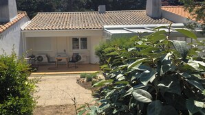 A house with a tiled roof, a patio with chairs, and a garden. - Charming, renovated, air-conditioned single-storey house on the edge of a forest. (Saint-Jean-de-Monts)