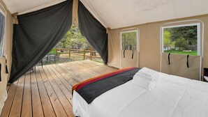 Una tenda arredata con un letto, una finestra e vista sulla natura.