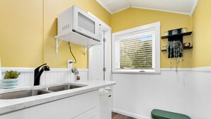 A kitchen with a white countertop, a built-in microwave, a sink, and a window with blinds. - Cabin 2- Youngs Gulch (Bellvue)