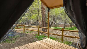 Um deck de madeira com vista para uma área arborizada e um cercado de bambu.