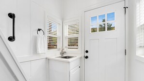 Un bagno bianco con lavandino, portasci asciugamani e una porta con finestra.