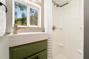 Un bagno con un lavandino bianco, un armadietto verde e una doccia con porta bianca.