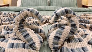Ein Schlafzimmer mit einem Bett, Kissen, einer Decke und einem Wandbild.