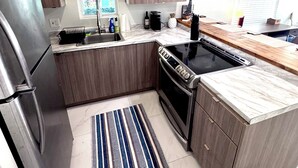 Eine moderne Küche mit Holzausstattung, einem Edelstahlkühlschrank, einem eingebauten Backofen und einer schwarzen Kochstelle.