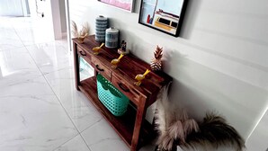 Ein moderner Flur mit einem Holztischchen, gerahmten Bildern und einem an der Wand montierten Fernseher.