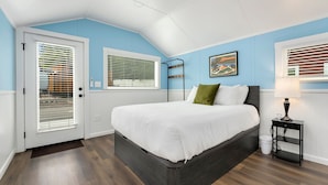 Ein Schlafzimmer mit Bett, Nachttisch, Fenster mit Jalousien, Tür und Deckenleuchte.