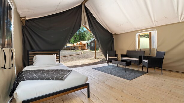Una habitació amb tenda, un llit, una taula petita i una cadira.
