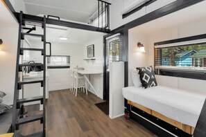 A compact studio apartment with a loft bed, kitchenette, and a small dining area. - Tiny 5- Profile Rock (Bellvue)