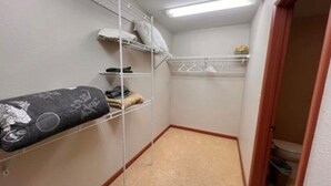 Ein kleiner, schmaler Raum mit einem Etagenbett, einem Metallregal und einer Tür zu einem Badezimmer.