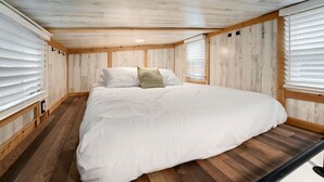 Una camera da letto con un letto grande, pareti in legno e un soffitto spiovente.