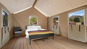 Una habitación con carpa, una cama, una silla y dos ventanas.