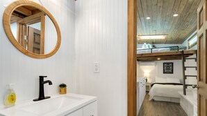 A modern bathroom with a white vanity, a round mirror, and a black faucet. - Tiny 2- Sleeping Elephant (Bellvue)